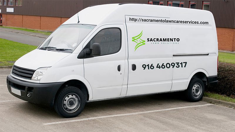 A white van parked in a spacious parking lot under clear blue skies.